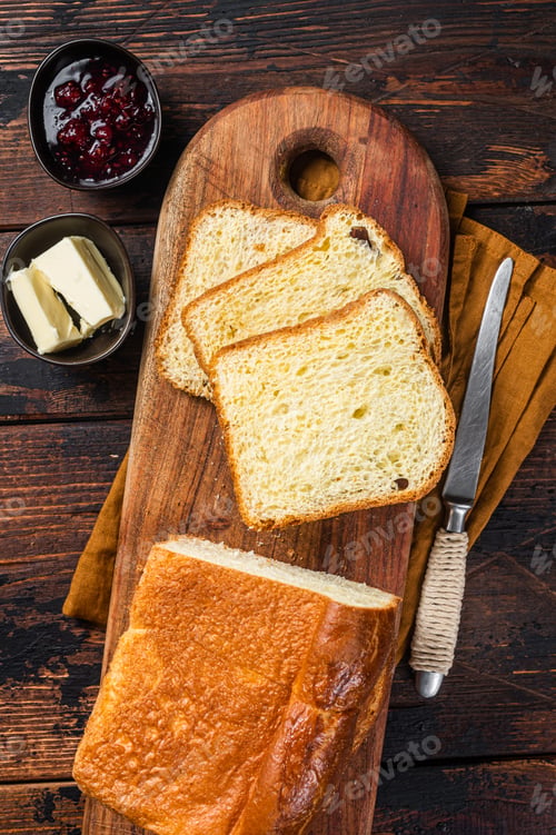 Preview: Brioche bread on breakfast table with butter and jam. Wooden background. Top view