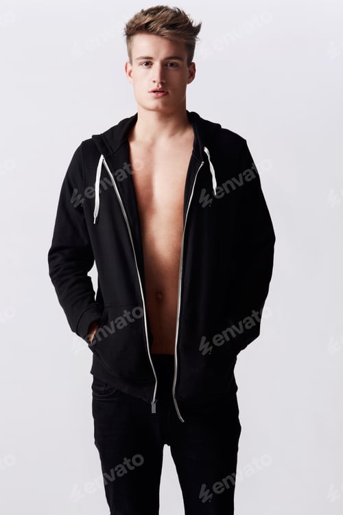 Preview: Studio portrait of young attractive man wearing a hoodie standing with hands in pockets