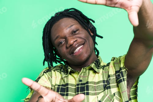 Preview: Young black man with dreadlocks smiling and making frame gesture
