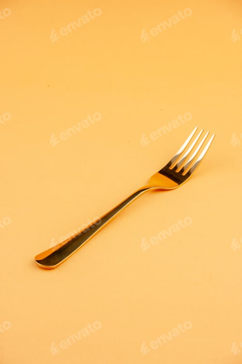 Preview: Close up view of elegant shiny golden stainless spoon on isolated yellow background with free space