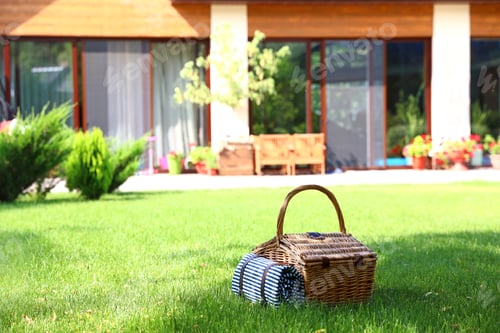 Preview: Picnic basket with blanket on green lawn in garden. Space for text