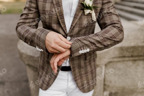 Preview: Groom in brown plaid jacket examines ring on finger. Wedding agency ad.