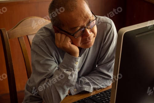 Preview: Asian businessman sitting and analyzing his works in the office room.