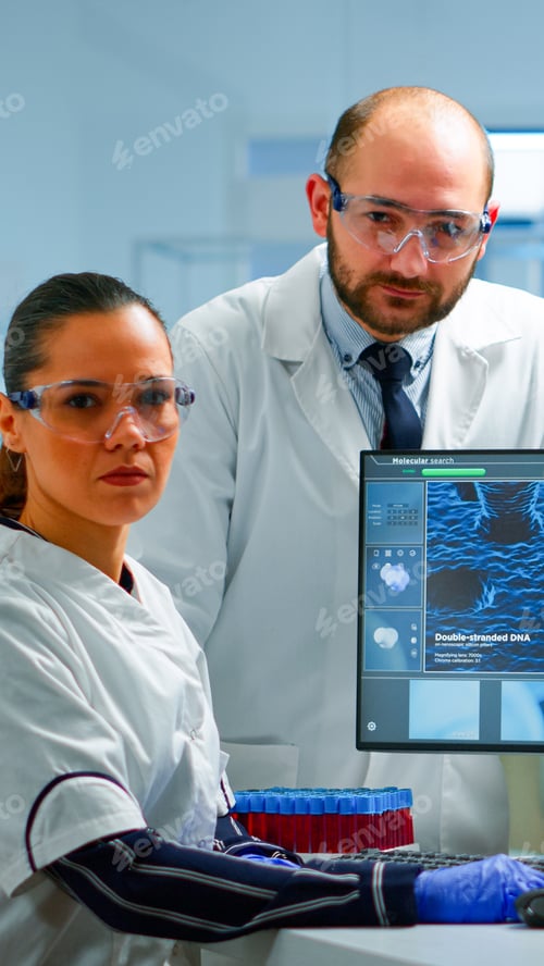 Preview: Team of scientists sitting in laboratory looking at camera
