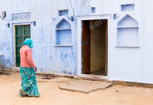 Preview: Unrecognised woman in traditional clothing walking past blue houses in jodhpur india