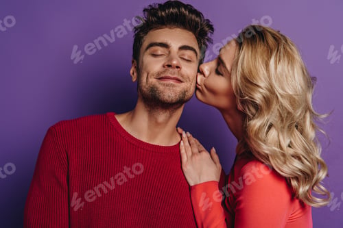 Preview: pretty girl kissing happy boyfriend standing with closed eyes on purple background