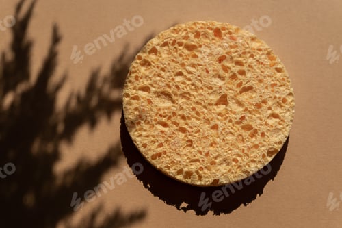 Visualização: close-up de esponja redonda natural de celulose para limpeza facial e remoção de maquiagem com plantas modernas