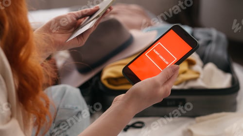 Preview: Unrecognizable traveler woman at bedroom holding mobile phone red screen sms message notification