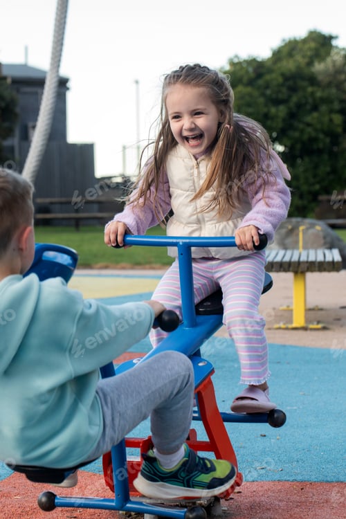Preview: Joyful children playing on seesaw at playground on a sunny day