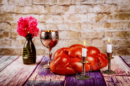 Preview: Shabbat candles in candlesticks of loaves challah for Shabbat wine in a kiddush cup with flowers