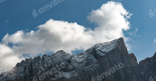 Preview: White cloud above rocky mountain peak and blue sky. Nature landscape. Dolomite rocky mountains