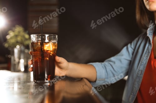 Preview: Woman with glass of refreshing cola at bar counter, closeup