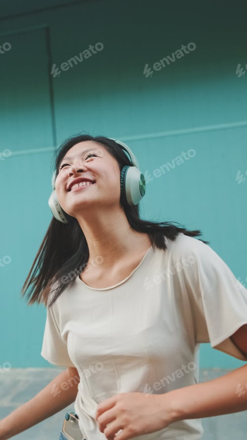 Preview: Happy beautiful brunette girl in headphones listens to music and dances
