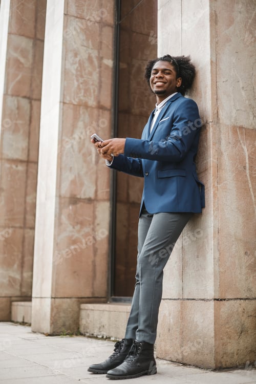 Preview: young african american businessman using mobile phone outside of the office