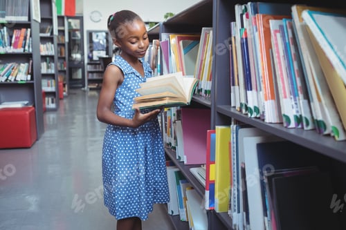 Preview: Girl reading book by shelf in library