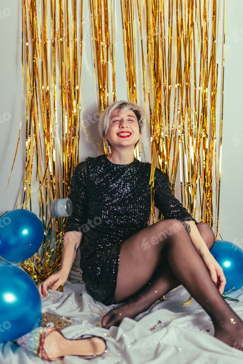 Preview: Young millennial blonde woman celebrating New Years Eve. Glitter sparkling confetti.