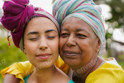 Preview: Happy african mother and daughter having tender moment outdoor while wearing traditional clothes