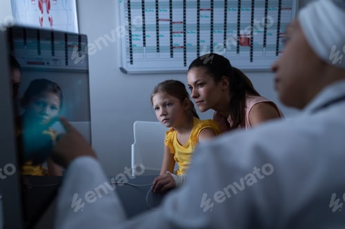Preview: Mature female doctor showing medical report to patient with computer in clinic at hospital