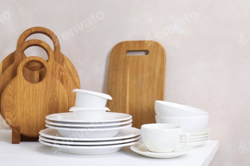 Preview: Different clean white dishware and wooden cutting boards on counter in kitchen