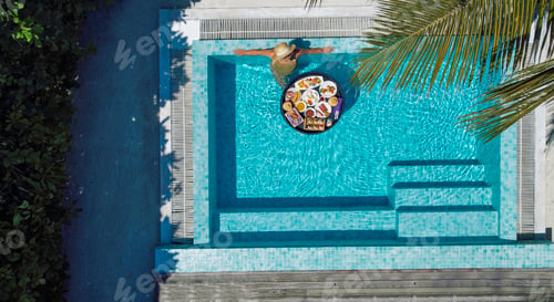 Preview: A young woman in a swimsuit relaxes in an outdoor pool.