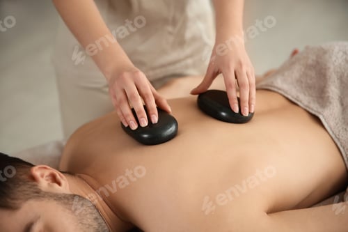 Preview: Man receiving hot stone massage in spa salon, closeup