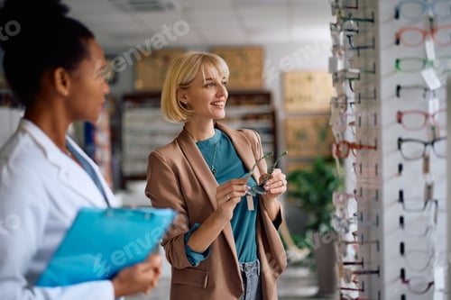 Preview: Happy woman choosing new frame for her eyeglasses in a pharmacy.