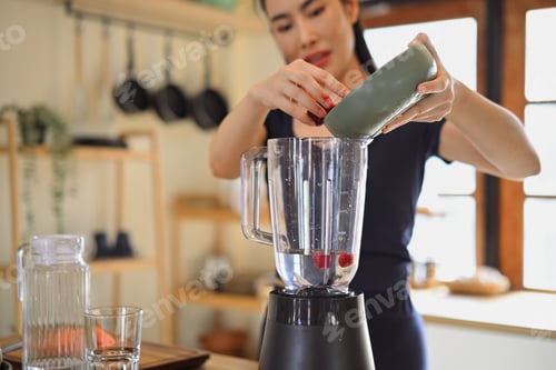 Preview: Happy woman blending fresh berries at home, enjoying modern lifestyle