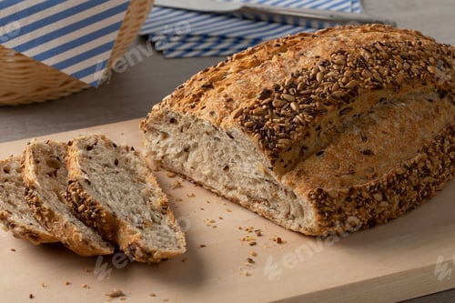 Preview: Fresh loaf and slices of country bread and seeds close up on a cutting board