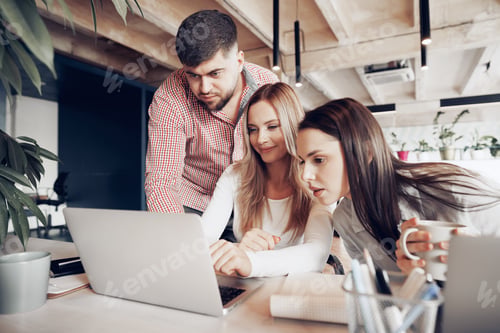 Preview: Two female and one male business partners looking at computer screen and discussing their project