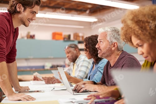 Preview: Teacher Helping Mature Man Attending IT Class In Community Centre