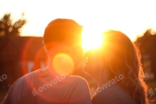 Preview: A heartwarming image of a couple's silhouettes against a vibrant sun setting or rising in the backgr