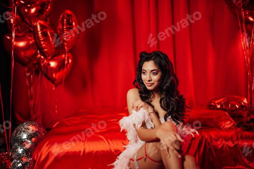 Preview: Beautiful asian sexy smiling girl in undies sitting on bed posing with feather boa in red balloons