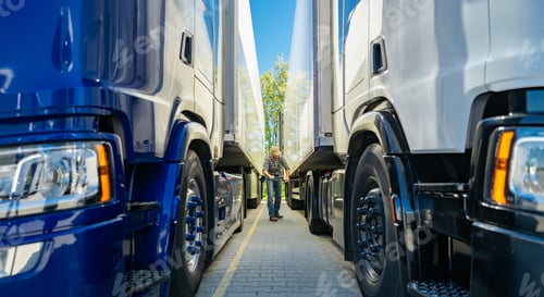 Preview: Two Large Semi-Trucks Parked Closely Together in a Transportation Yard During Daylight Hours