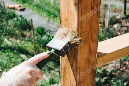 Preview: A gloved hand holds a brush and covers a wooden pole with varnish.