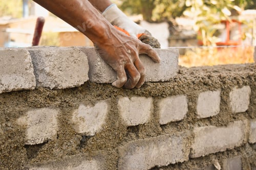 Preview: Closeup of a man building a wall with bricks, outdoors during daylight