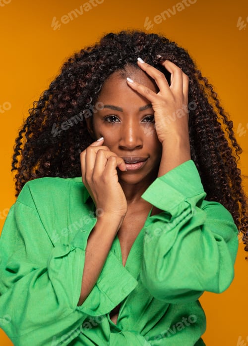 Preview: Confident black woman with curly hair posing against orange background