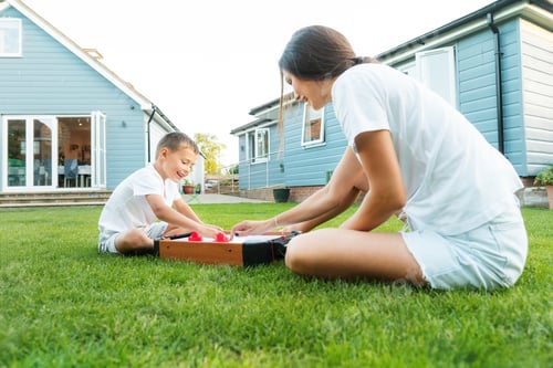 Preview: Joyful little boy and his young mother are playing portable air hockey in the garden. Fun Playing