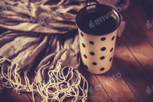 Preview: Cup of coffee and scarf on wooden table.