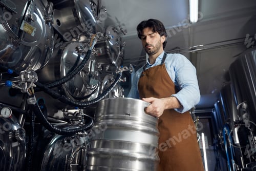 Preview: Brewer man is diligently working on a large metal barrel