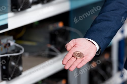 Preview: cropped shot of businessman in suit holding bitcoin at cryptocurrency mining farm
