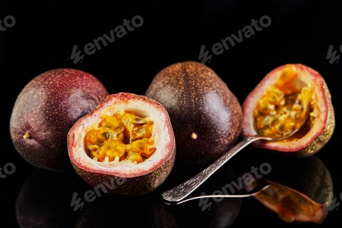 Preview: Passiflora is cut into two halves with a spoon inside and two whole isolated on a black background