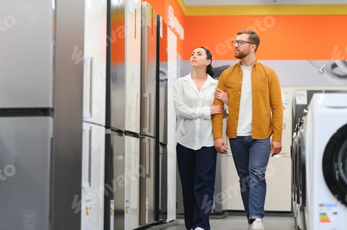Preview: couple, satisfied customers choosing fridge in appliances store