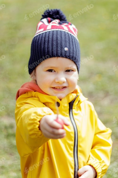 Preview: Toddler in Yellow Jacket Holding Small Item Outside