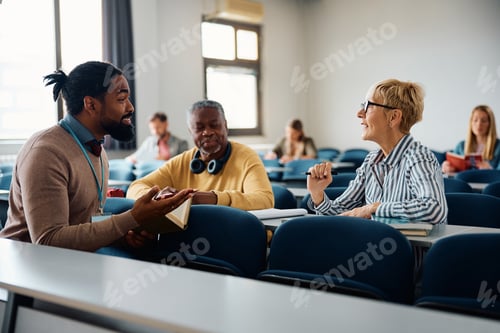 Preview: Black adult education teacher talking to his students during a course in the classroom.