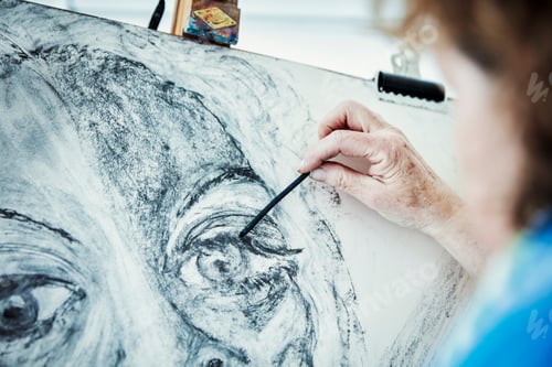 An artist working at her easel, drawing with charcoal on paper