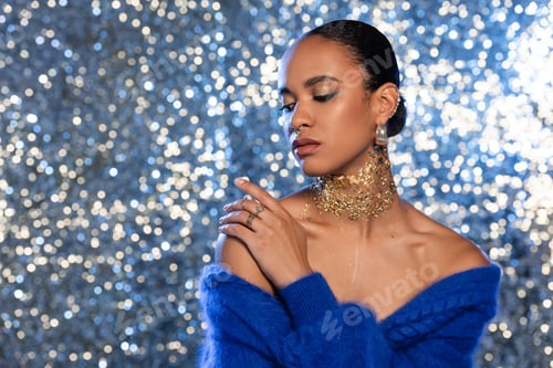 Preview: Pretty african american woman with foil on neck touching bare shoulder on sparkling background