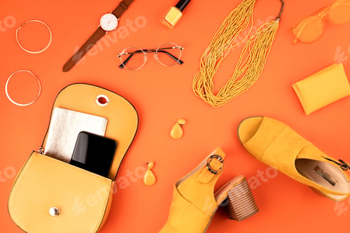 Preview: Flat lay with woman fashion accessories in yellow color over orange yellow textured background