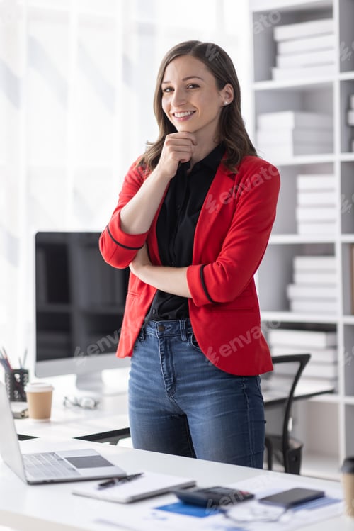Preview: Excited Happy Asian young woman using phone and laptop sitting on a desk office in the day at office