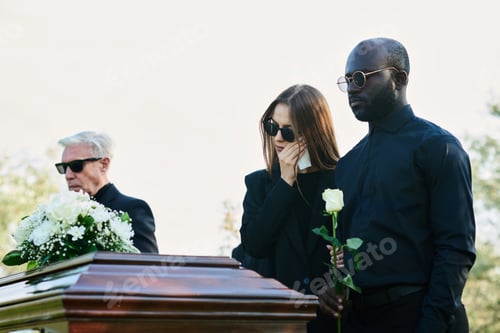 Preview: Young mourning man with white rose standing by his wife wiping tears