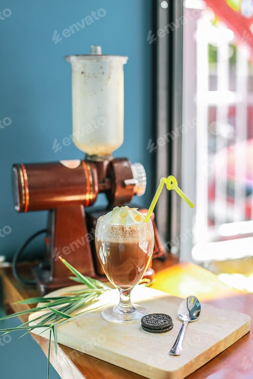 Preview: Cold drink with whipped cream on it in a glass with a cookie on a wooden board on the table